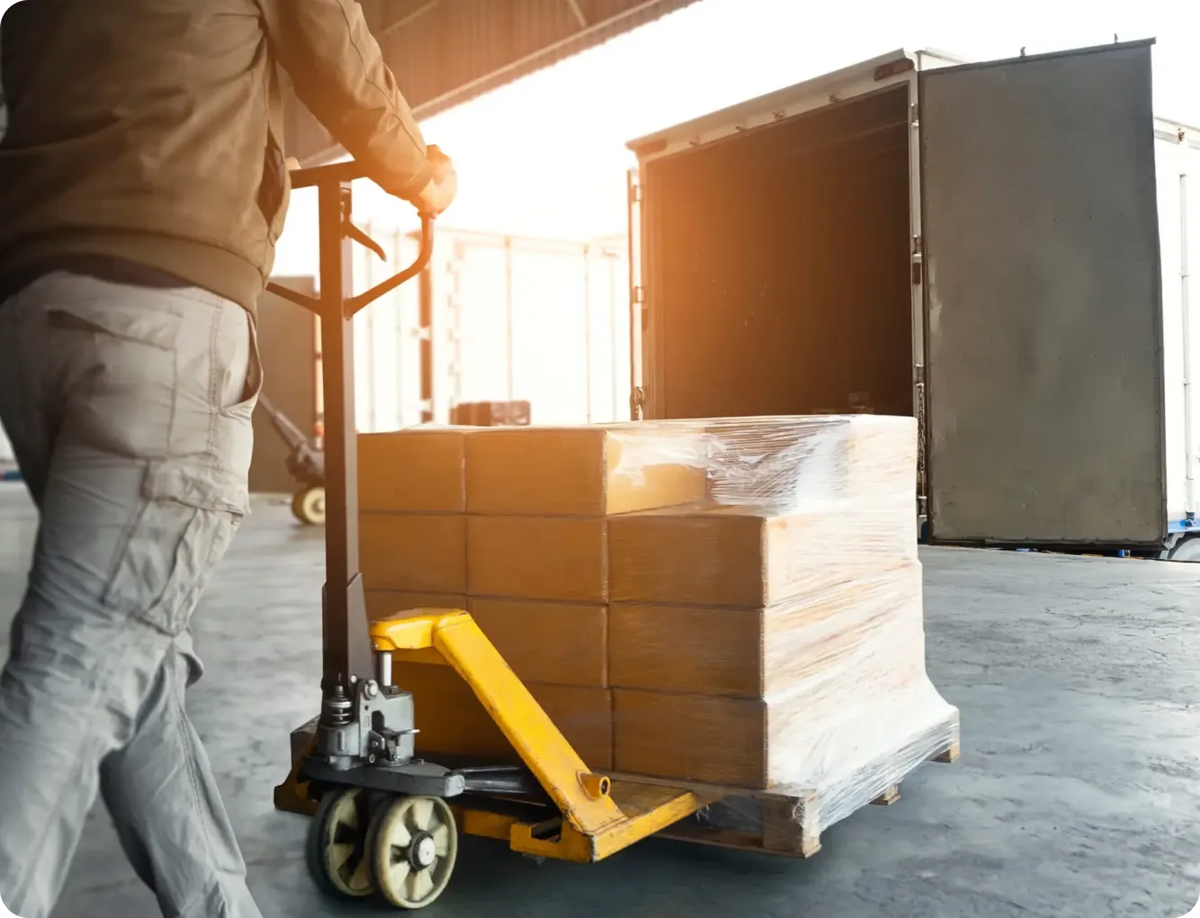 Worker moving IT equipment on a pallet jack in a logistics facility
